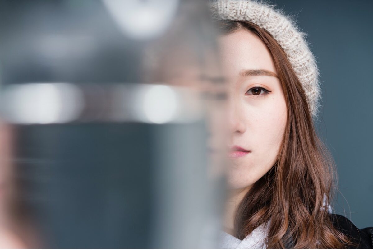 A woman's face is half obscured by out-of-focus glass