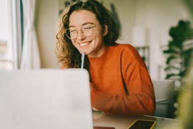 Young woman smiling while looking at laptop screen