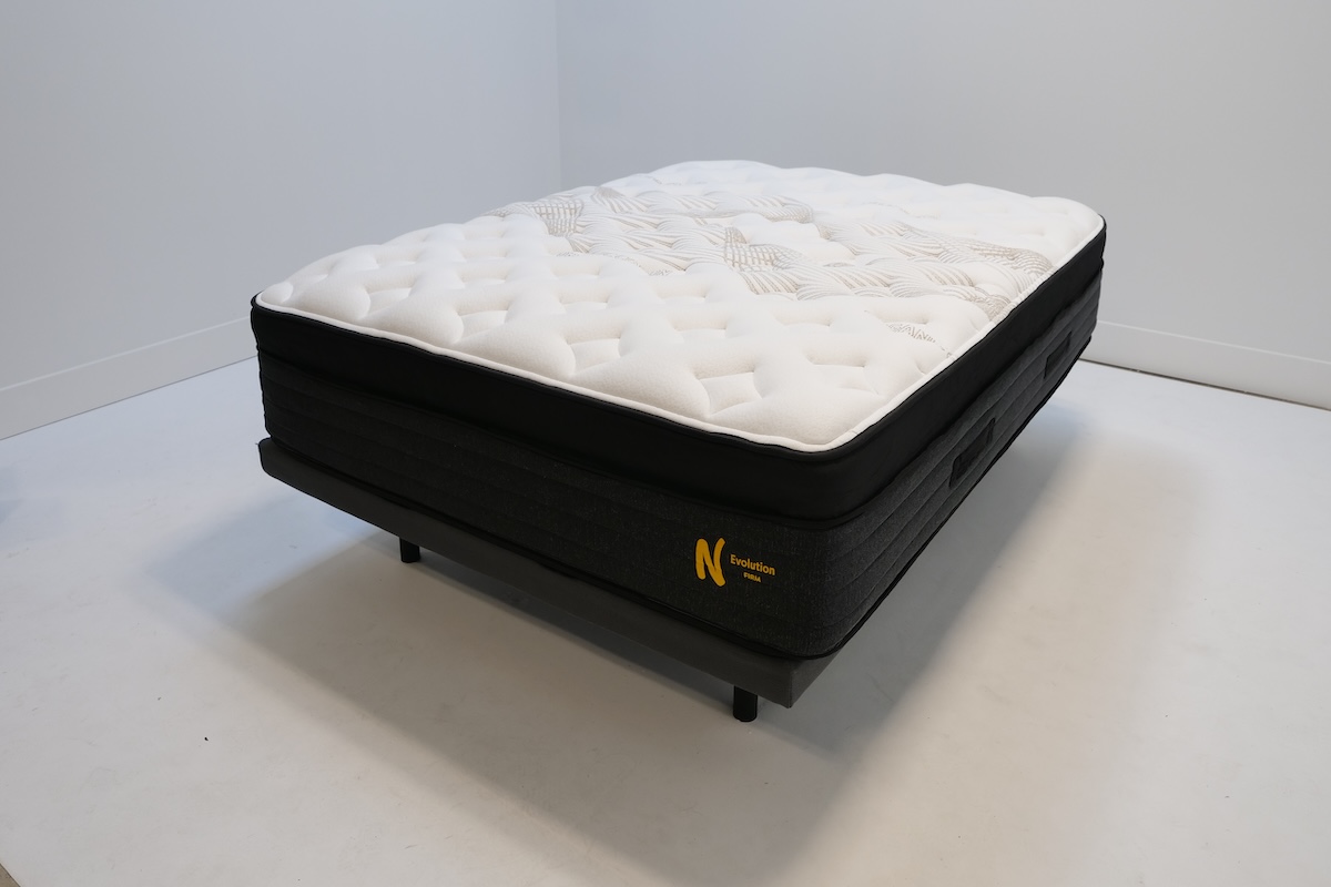  The black and white Nolah Evolution on a basic bed frame in a white room.