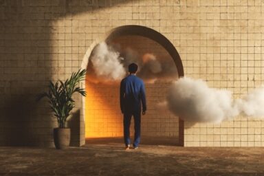 A man standing in front of a cloud-filled doorway.