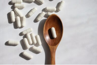 A wooden spoon sits amidst probiotic capsules