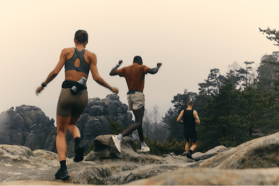 Three people running over a rocky hiking trail